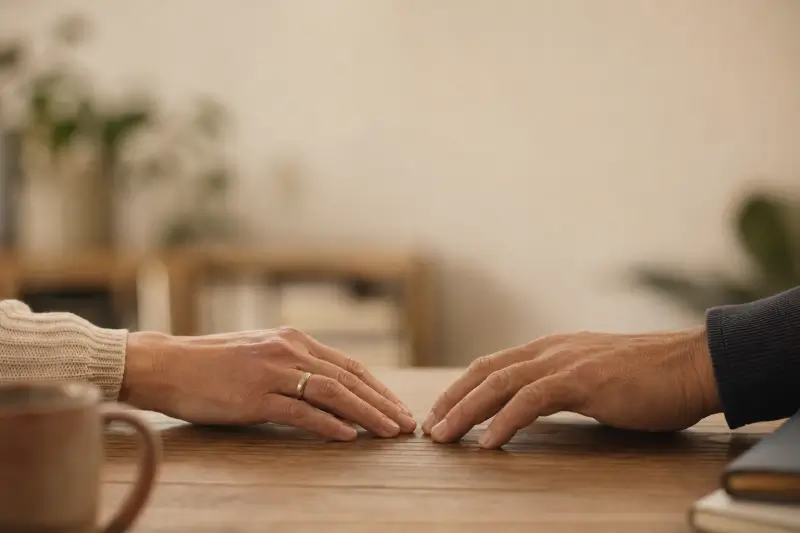 שתי ידיים על שולחן עץ, רגע אחרי שנפרדו זו מזו — גישור גירושין כאלטרנטיבה להליך משפטי
